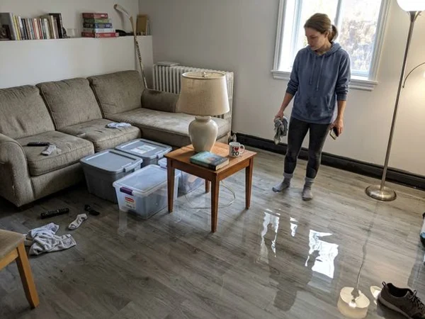 Ankle-deep standing water across a finished basement with floating storage bins