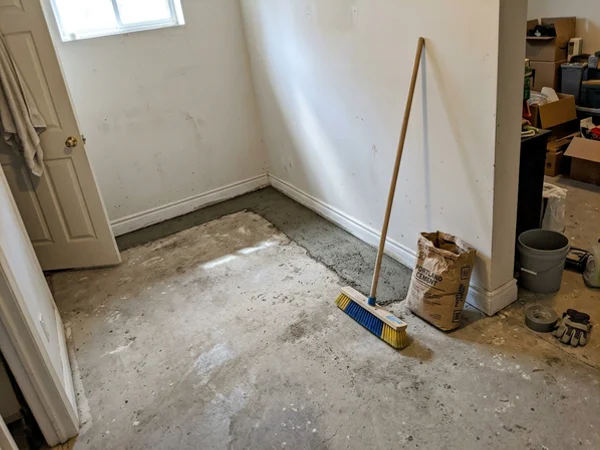 Basement floor with fresh concrete patch along the perimeter after interior weeping tile install