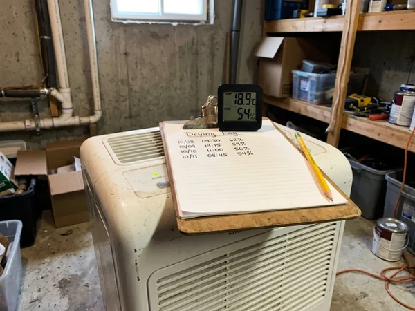 Thermo-hygrometer showing relative humidity and grains per pound beside a drying log